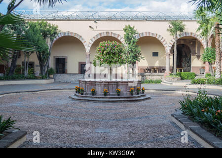 Il centro fontana al centro del cortile con arcate architettonico e vari alberi, all'Instituto Allende, in San Miguel De Allende, Messico Foto Stock