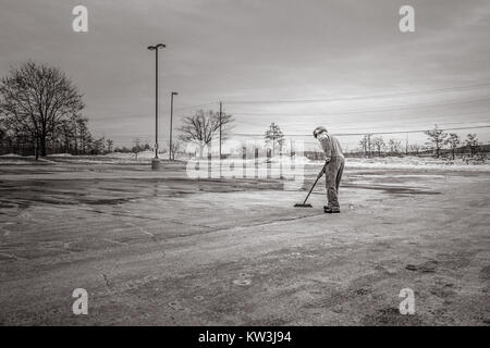 Una fotografia in bianco e nero raffigurante un uomo che cammina per una strada. L'immagine cattura un momento della vita quotidiana, con particolare attenzione al movimento del soggetto e all'ambiente urbano. Foto Stock