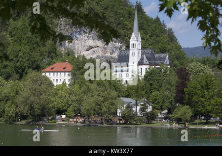 Questa fotografia di Bled, Slovenia, mostra il pittoresco paesaggio che circonda il lago di Bled, famoso per la sua splendida chiesa dell'isola e il castello arroccato sopra il lago. Popolare destinazione turistica, l'area è rinomata per la sua bellezza naturale e i suoi monumenti storici. Foto Stock