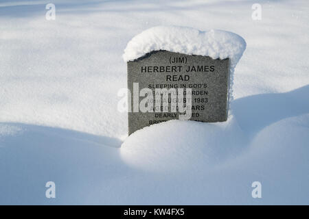 Coperta di neve lapide in San Bartolomeo del sagrato nel dicembre neve. Notgrove, Cotswolds, Gloucestershire, Inghilterra Foto Stock