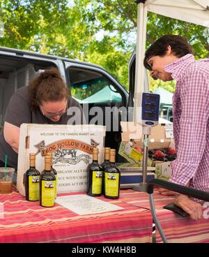 In un mercato agricolo in San Francisco Bay Area Cittadina di Danville, California, una donna effettua un acquisto da un rivenditore di rana Farm di cava, di una azienda agricola biologica situata in Brentwood, California, 13 agosto 2016. Foto Stock