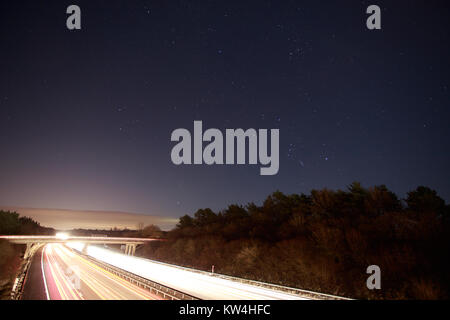 Streaming fari di traffico in autostrada di notte contro un cielo stellato Basingstoke Hampshire Foto Stock