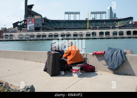 Un uomo senza tetto guarda attraverso McCovey Cove verso ATT Park, il baseball stadium di San Francisco Giants, nel bacino di Cina quartiere di San Francisco, California, 21 agosto 2016. Foto Stock