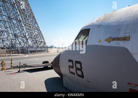 Struttura metallica di hangar si è visibile lungo con la porzione di naso di un aereo militare in mostra al campo di Moffett museo storico, all'interno dell'area protetta della NASA Ames Research Center campus in Silicon Valley Town di Palo Alto, California, 25 agosto 2016. Hangar uno, che è tra le più grandi del mondo free-standing strutture, stata affittata a Google Inc planetario di affiliazione Ventures nel 2016 (insieme a Moffett Field) per 60 anni a un costo di 1,6 miliardi di dollari, contingenti alla ristrutturazione della società la struttura, California. Foto Stock