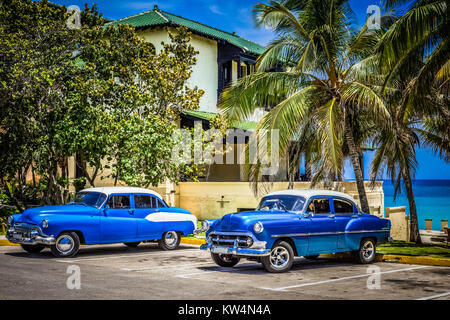 American blu Chevrolet e Buick otto auto classica con il bianco rofo parcheggiato sulla spiaggia sotto le palme a Varadero Cuba - Serie Cuba Reportage Foto Stock