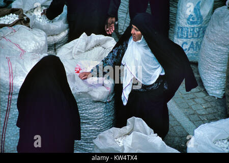 Le donne turche indossando il tradizionale abito islamico, o Hijab, circondato da sacchetti di bozzoli di seta nel bazaar di seta o Koza Han, Bursa, Turchia Foto Stock