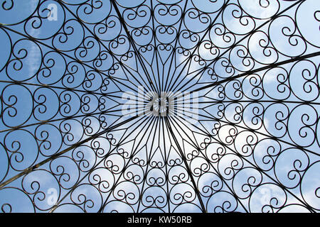 Vista verso l'alto di modelli astratti di un ferro battuto gazebo contro un cielo blu con luce cloud. Foto Stock