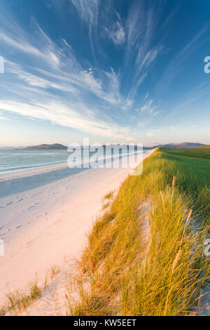 Strong golden sun accende la spiaggia incontaminata e le dune di sabbia lungo la costa occidentale di Berneray con le colline di Harris dietro, Ebridi Esterne, Scozia Foto Stock