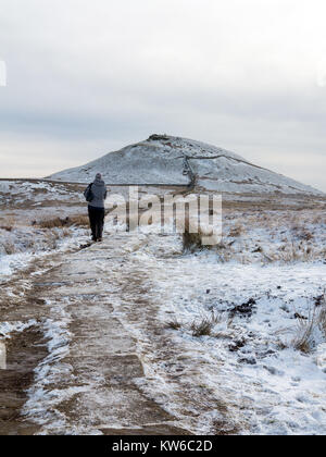 Donna che cammina verso Shutlingsloe hill nella neve il terzo punto più alto nel Cheshire a 506 metri dall'approccio attraverso la foresta a Macclesfield Foto Stock