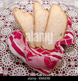 Tre fette di pane in un cestello con un panno rosso su una parte superiore di una tavola con un bianco e rosso panno della tabella Foto Stock