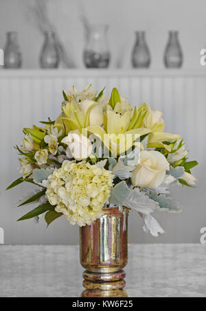 Moderno, tutto bianco fiori in un vaso di argento contro un nero e sfondo bianco. Foto Stock