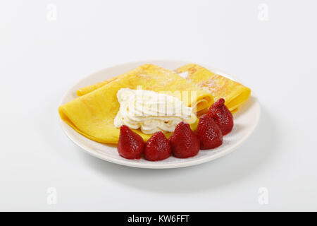 Piastra di sottili frittelle (crepes) con fragole e panna montata Foto Stock