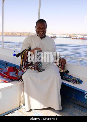 Sorridente uomo egiziano con bracciata di bella mano di collane in vendita seduti in barca sul fiume Nilo Foto Stock