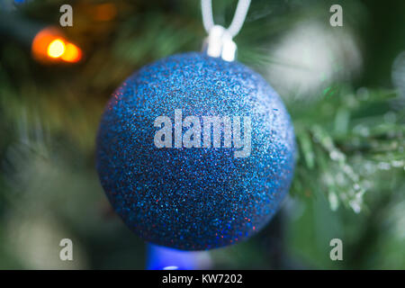 Un closeup di una singola decorazione blu bauble appeso da a. Albero di Natale Foto Stock