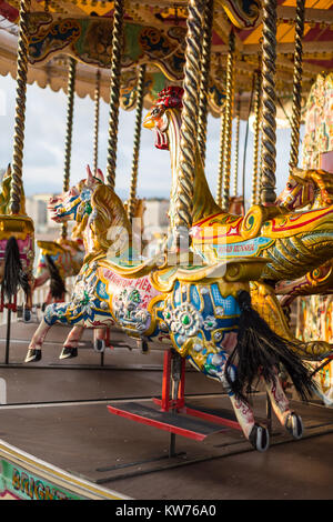 Verniciato colorato cavalli nel sole di sera su una giostra sul molo di Brighton Foto Stock