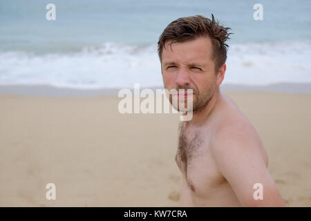 Ritratto di un attraente caucasian giovane uomo su una spiaggia tropicale Foto Stock