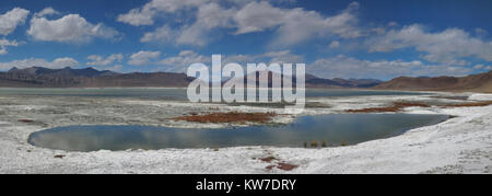 Il turchese del lago tra le alte montagne del deserto di sale, colline di montagna in background, nel blu del cielo nuvole, l'Himalaya, panorama. Foto Stock