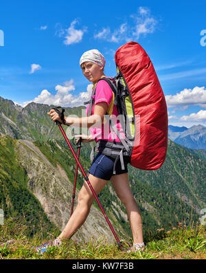 Escursionismo. Viaggiatore con zaino grande passeggiate lungo il bordo della passata utilizzando bastoncini da trekking per l'equilibrio. Libera il turismo nelle montagne della Siberia orientale Foto Stock