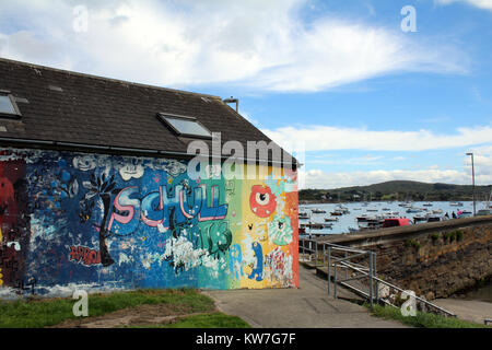 edificio coperto di graffiti vicino al porto in una giornata di sole Foto Stock