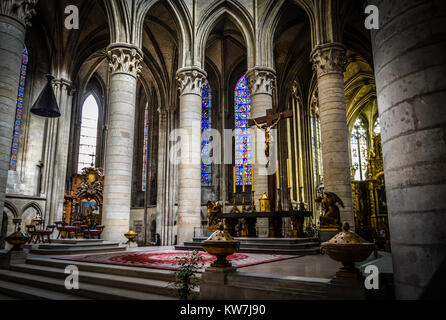 La solenne, buio interiore della cattedrale di Notre Dame a rouen Francia, con l'altare e colorate le finestre di vetro macchiate. Foto Stock