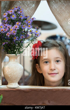 Una bambina guarda fuori di un giocattolo di casa Foto Stock