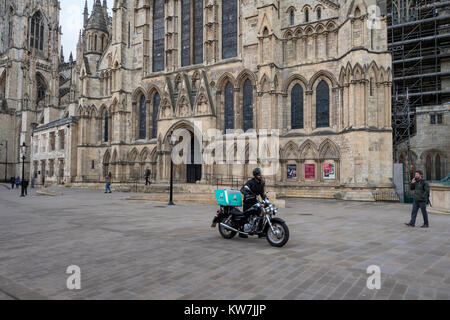 York Centre - ingresso alla Cattedrale di York Minster e piazza pedonale dove la gente a piedi & Deliveroo pilota spinge la moto - North Yorkshire, Inghilterra, Regno Unito. Foto Stock