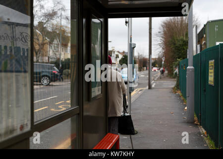 La donna in attesa presso la fermata degli autobus sulla strada Hainault, Leytonstone, Londra. Foto Stock