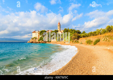 Onde sulla spiaggia con il famoso monastero domenicano nella città di Bol, isola di Brac, Croazia Foto Stock