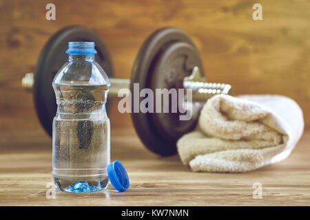 Concetto di attrezzature per il fitness con il manubrio, bottiglia di acqua e asciugamano. Foto Stock