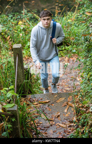 Ragazzo adolescente salire a piedi a passi concreti nei pressi di un canale in una giornata autunnale Foto Stock