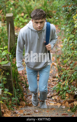 Ragazzo adolescente salire a piedi a passi concreti nei pressi di un canale in una giornata autunnale Foto Stock