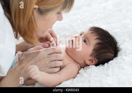 Felice madre guardando il bambino in camera da letto Foto Stock