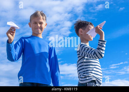 I bambini di gettare carta bianca piani accanto all blue sky Foto Stock