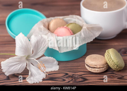 Macaron colorati torta in confezione regalo, una tazza di caffè e bianco fiori di ibisco, concetto di vacanza Foto Stock