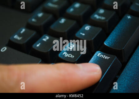 Dito che preme il tasto invio close up Foto Stock