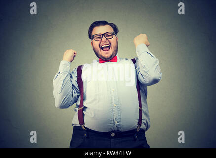 Giovane uomo cercando vittorioso tenendo i pugni fino celebrando la vittoria. Foto Stock