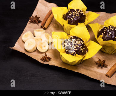 Muffin alla banana avvolto in carta gialla su sfondo nero, vista dall'alto Foto Stock