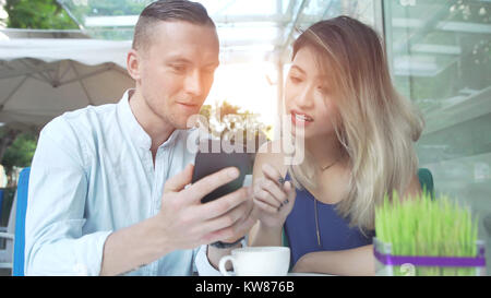 Coppia multiculturale utilizzando app sullo smartphone insieme Foto Stock