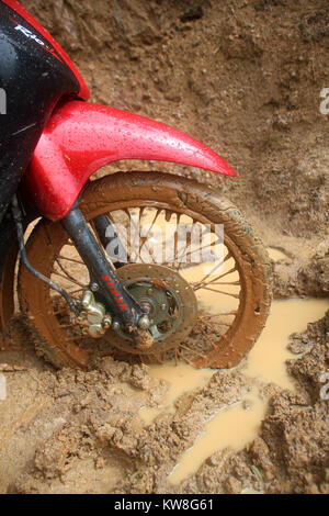 Moto ruota anteriore sul bagnato strada sporca. Laos Foto Stock