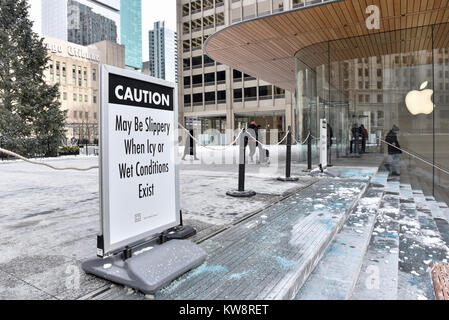 Chicago, Stati Uniti d'America. Il 31 dicembre 2017. Segnali di avvertimento i passanti di caduta di ghiaccio sono sul display intorno alla nuova ammiraglia Apple Store di North Michigan Avenue, vicino al fiume Chicago. L'edificio, progettato da architetti britannici Foster + Partner, ha un tetto di forma simile a quella del coperchio di un computer portatile Apple e sembra mancare visibile grondaie. Ghiaccioli che si sono formate nella corrente a temperature sotto lo zero sono caduto a terra al di sotto di pericolo per il pubblico e il negozio è attualmente rivolto critiche dai locali di sviluppare una soluzione. Credito: Stephen Chung / Alamy Live News Foto Stock