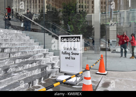 Chicago, Stati Uniti d'America. Il 31 dicembre 2017. Segnali di avvertimento i passanti di caduta di ghiaccio sono sul display intorno alla nuova ammiraglia Apple Store di North Michigan Avenue, vicino al fiume Chicago. L'edificio, progettato da architetti britannici Foster + Partner, ha un tetto di forma simile a quella del coperchio di un computer portatile Apple e sembra mancare visibile grondaie. Ghiaccioli che si sono formate nella corrente a temperature sotto lo zero sono caduto a terra al di sotto di pericolo per il pubblico e il negozio è attualmente rivolto critiche dai locali di sviluppare una soluzione. Credito: Stephen Chung / Alamy Live News Foto Stock