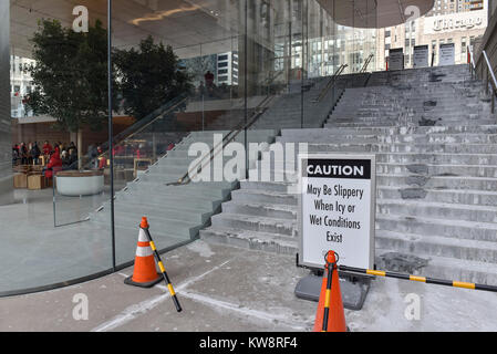 Chicago, Stati Uniti d'America. Il 31 dicembre 2017. Segnali di avvertimento i passanti di caduta di ghiaccio sono sul display intorno alla nuova ammiraglia Apple Store di North Michigan Avenue, vicino al fiume Chicago. L'edificio, progettato da architetti britannici Foster + Partner, ha un tetto di forma simile a quella del coperchio di un computer portatile Apple e sembra mancare visibile grondaie. Ghiaccioli che si sono formate nella corrente a temperature sotto lo zero sono caduto a terra al di sotto di pericolo per il pubblico e il negozio è attualmente rivolto critiche dai locali di sviluppare una soluzione. Credito: Stephen Chung / Alamy Live News Foto Stock