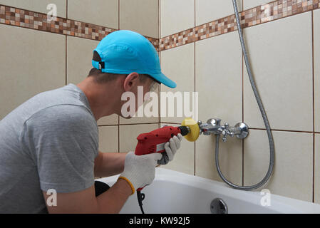 Professionale servizio di lucidatura del tema. Uomo con trapano bagno pulizia rubinetto Foto Stock