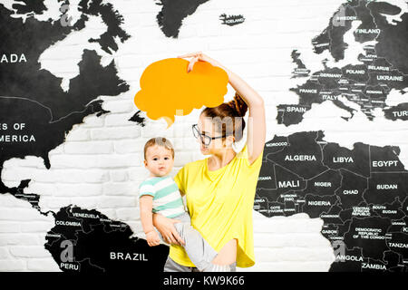 Uomo con una cupola colorata sopra la testa seduto in ufficio con la mappa del mondo sullo sfondo a sognare in viaggio Foto Stock