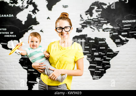 Uomo con una cupola colorata sopra la testa seduto in ufficio con la mappa del mondo sullo sfondo a sognare in viaggio Foto Stock