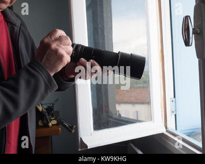 Fotografo presso la finestra con un teleobiettivo Foto Stock