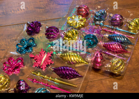 Due confezioni di plastica colorato e ornamenti in vetro seduto sul pavimento in legno Foto Stock