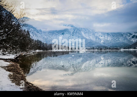 La straordinaria serenità del lago di Bohinj, Slovenia, è catturato in questa meravigliosa immagine, perfetta per ornare la parte anteriore di un biglietto di auguri di Natale o cartolina. Foto Stock