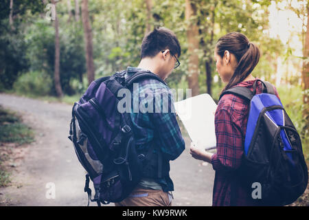 Gruppo asiatico di giovani escursioni con gli amici zaini camminare insieme e guardando la mappa e tenendo la fotocamera foto dalla strada e cercando felice ,Rela Foto Stock