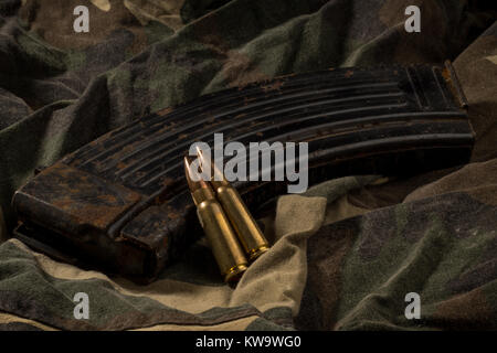 Rusty AK-47 magazine e elenchi puntati su camouflage sfondo tessili Foto Stock